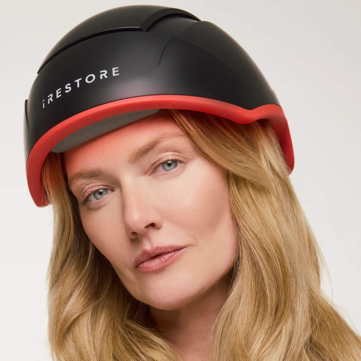 Woman wearing the iRESTORE Elite Hair Growth System on a light background