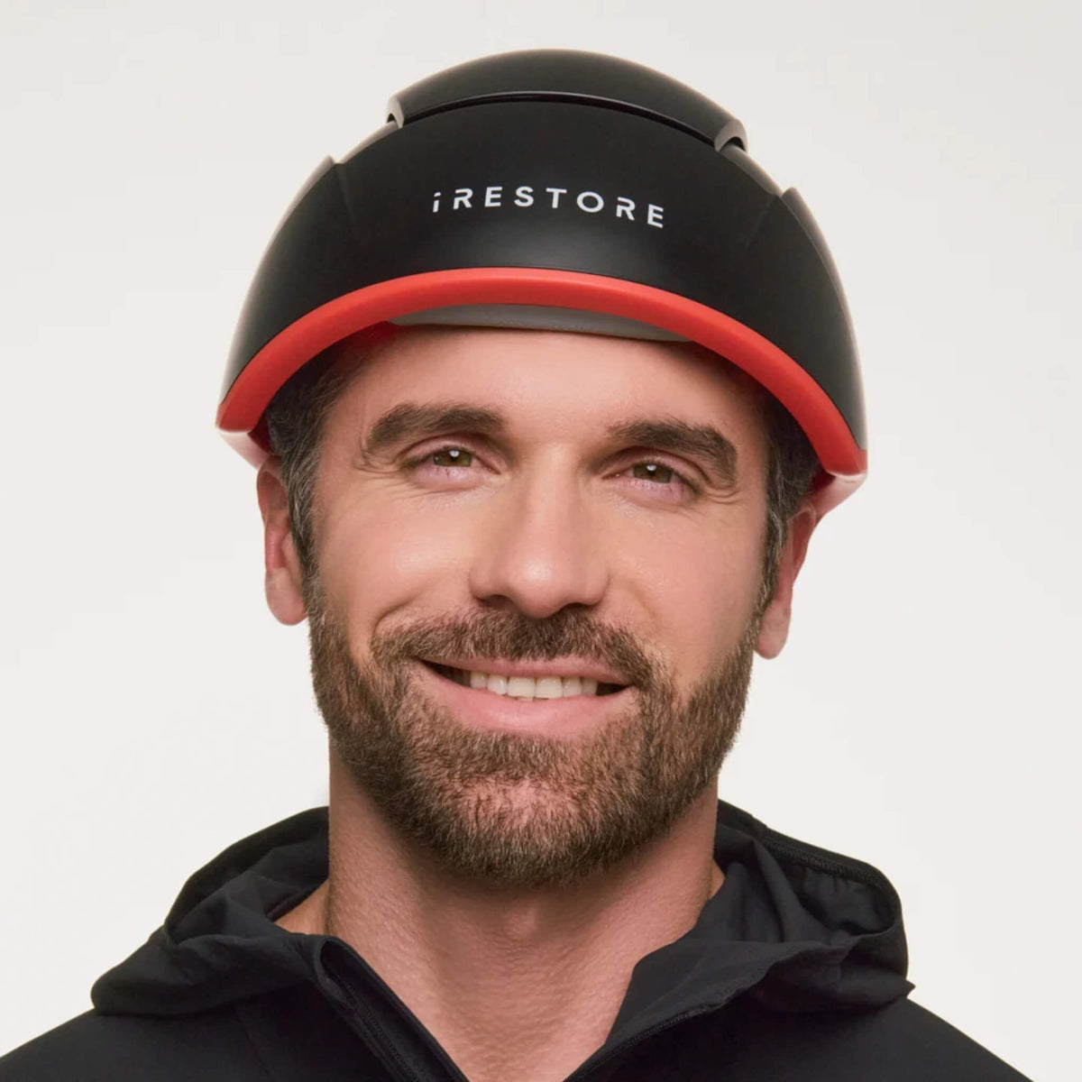 Man wearing the iRESTORE Elite Hair Growth System on a light background