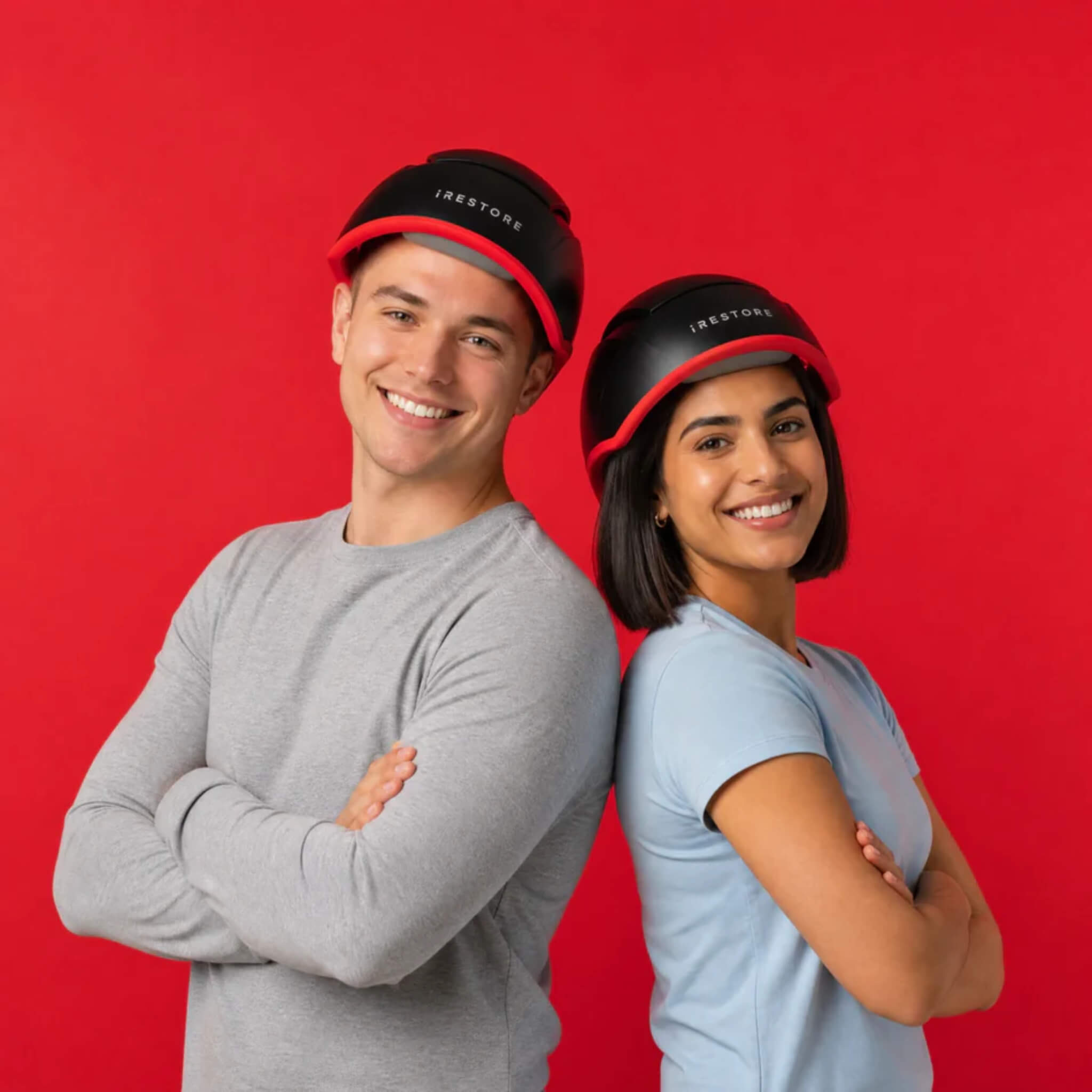 Man and woman wearing iRESTORE Elite laser hair growth system on red background showing unisex design