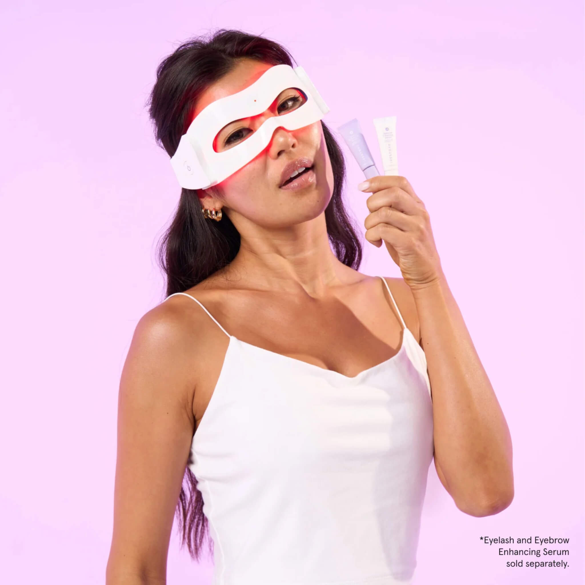 Woman wearing the iRESTORE Illumina Eye Mask against a pink background