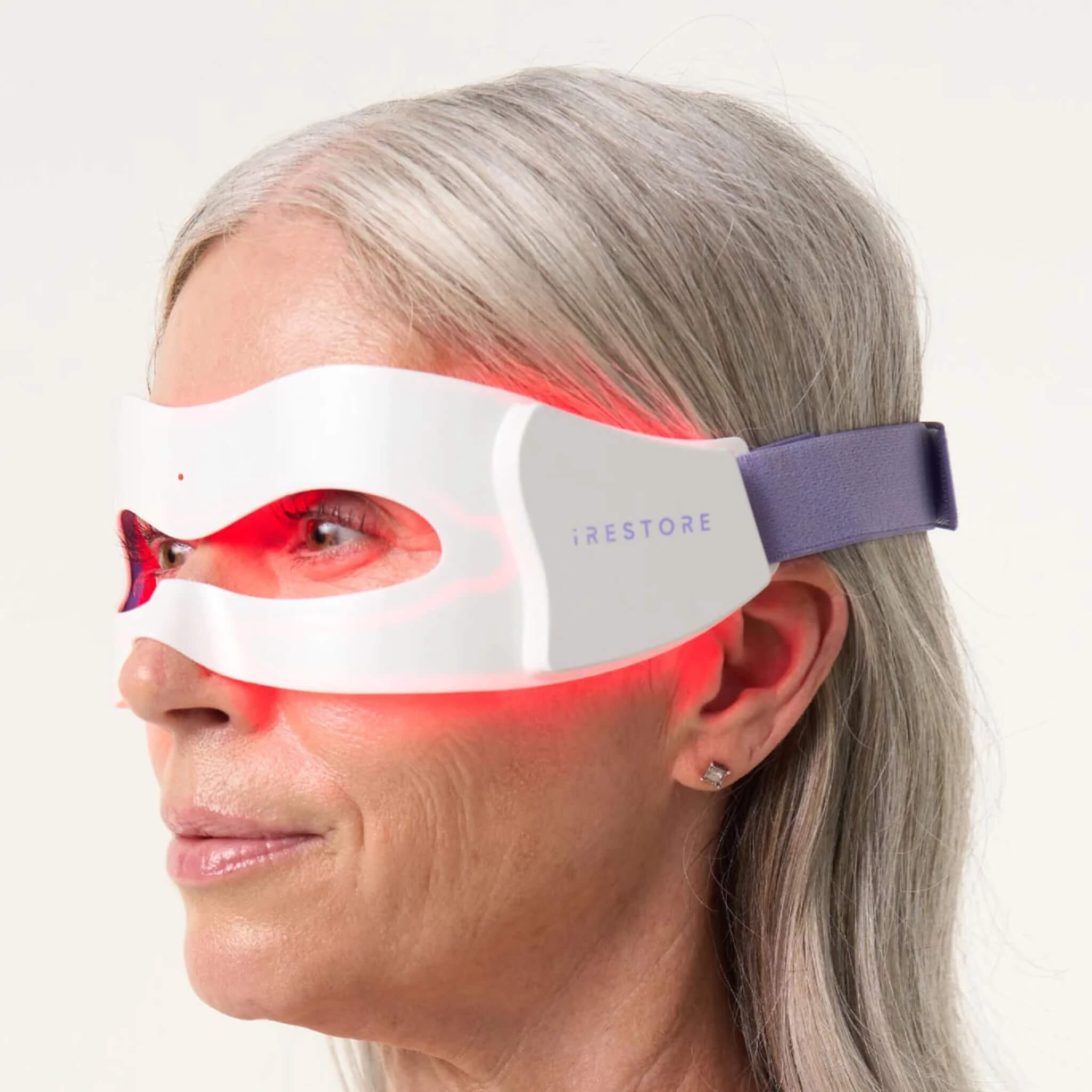 Woman wearing the iRESTORE Illumina Eye Mask in profile, red light illuminated