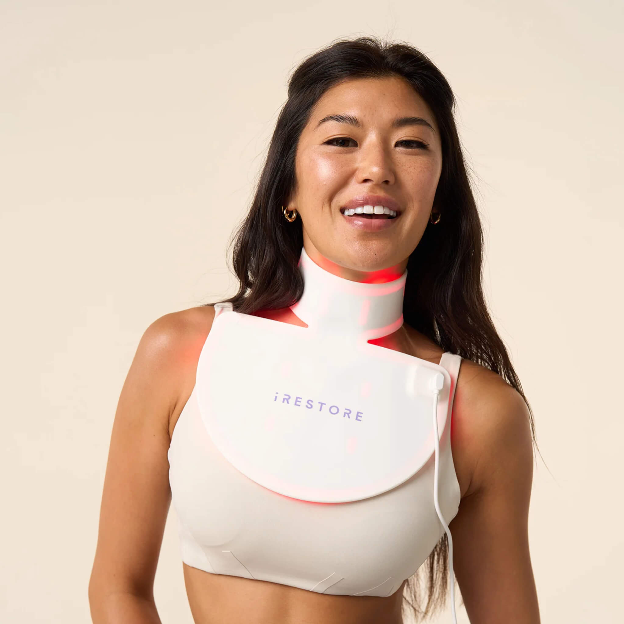 Woman wearing the iRESTORE Illumina Neck & Chest Mask over a beige top