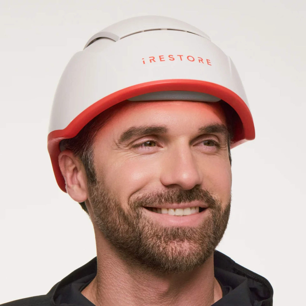 Man wearing the iRESTORE Professional Hair Growth System on a light background