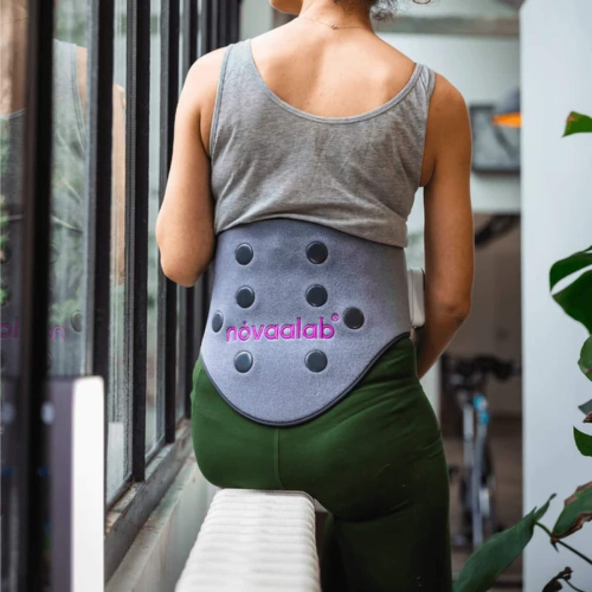 Back view of a woman wearing the NovaaLab Novaa Back Pad around her lower back and waist