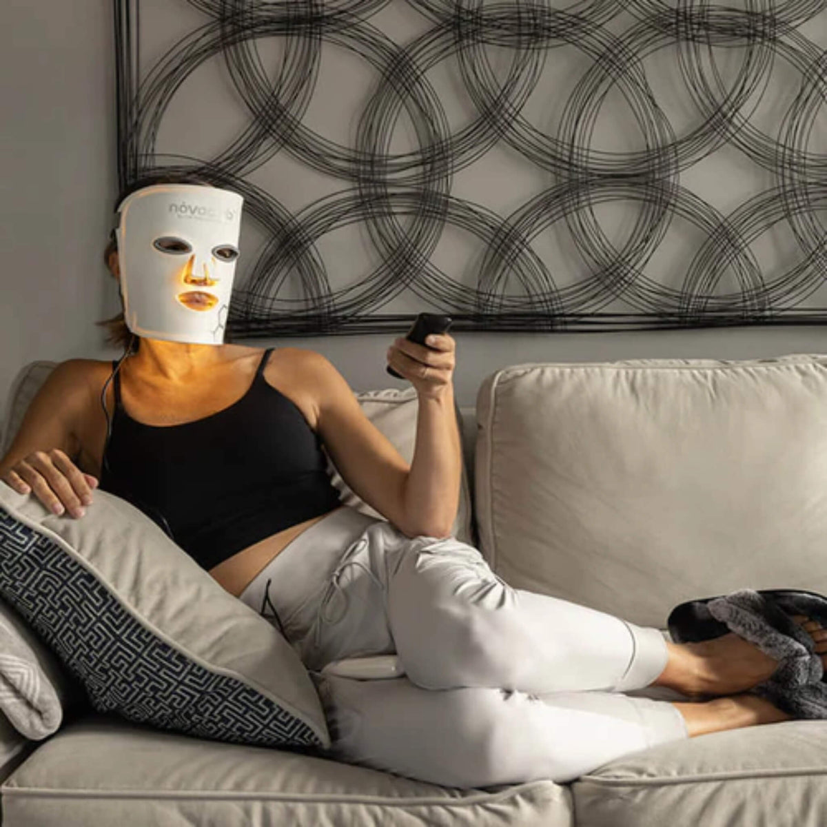 Woman relaxing on the couch during a hands-free NovaaLab Novaa Glow Therapy Mask session