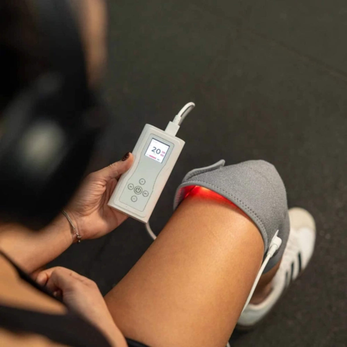 Hand holding the NovaaLab Novaa Knee Ultra battery remote showing a 20 minute session