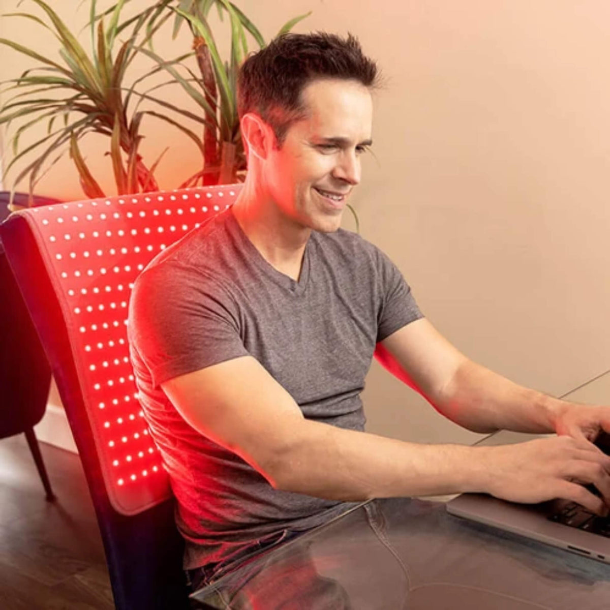 Man working at his desk with the NovaaLab Novaa Light Pad XL covering his back