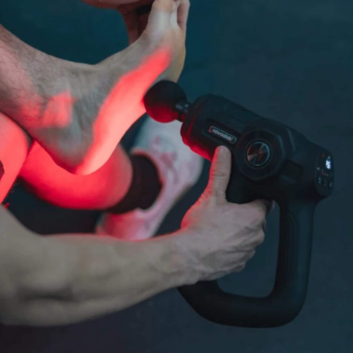 NovaaLab Novaa Pulse R percussion massage gun with the round head in use on the sole of a foot