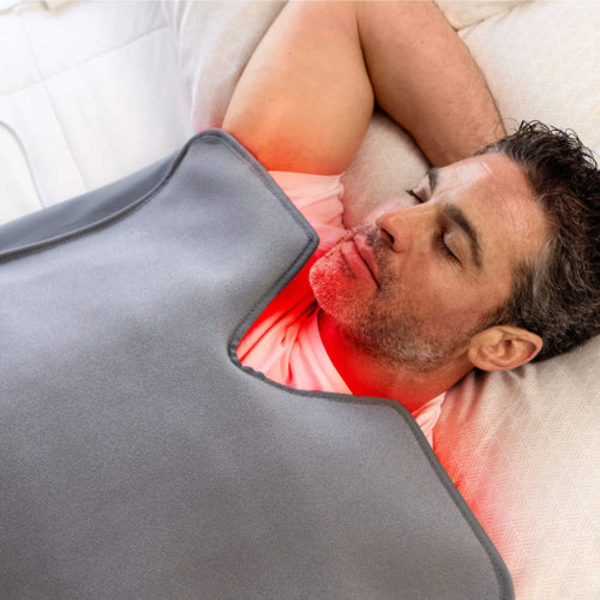 Man relaxing inside the NovaaLab Novaa Recovery Pod with red light glowing at the neckline