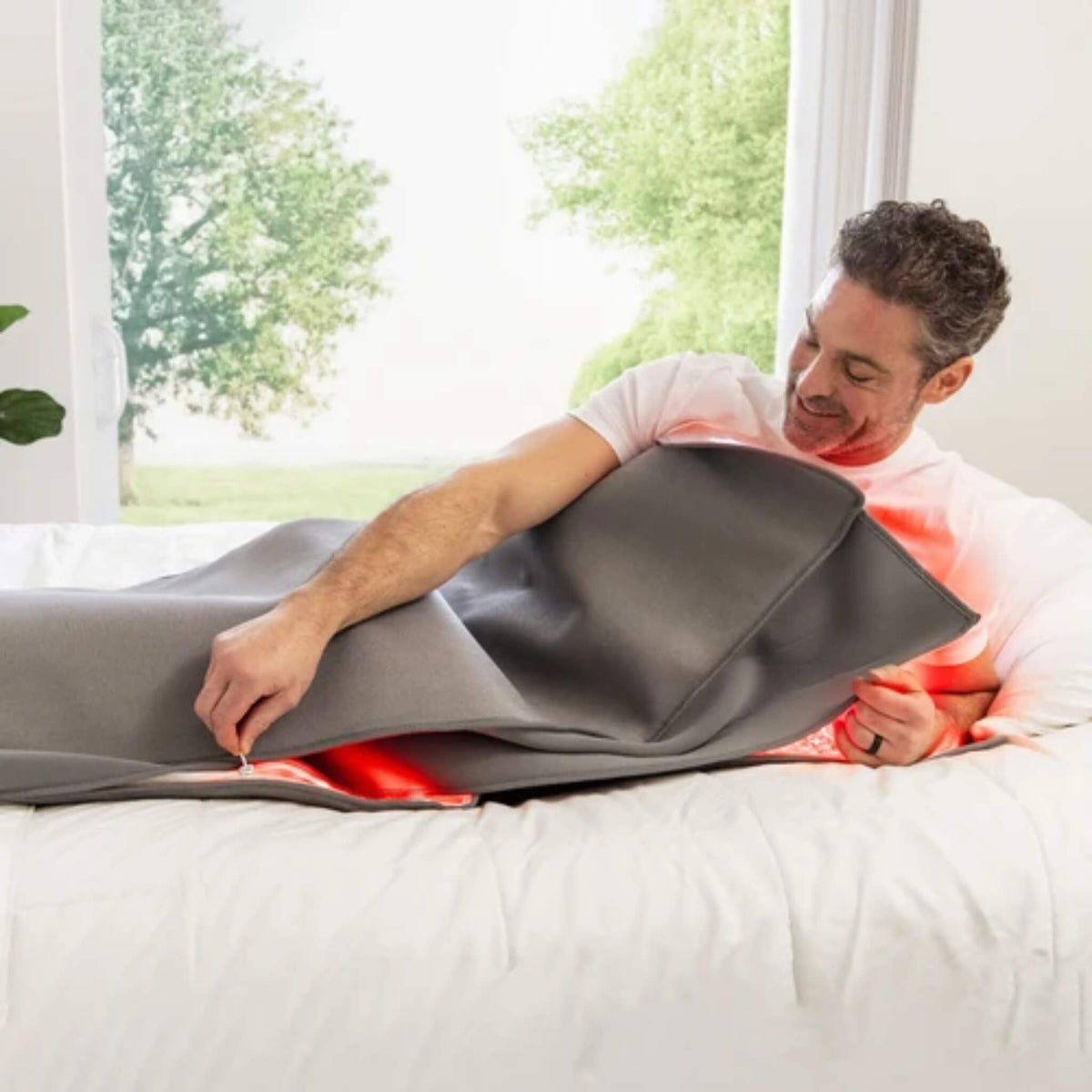 Man lying on a bed zipping the NovaaLab Novaa Recovery Pod closed