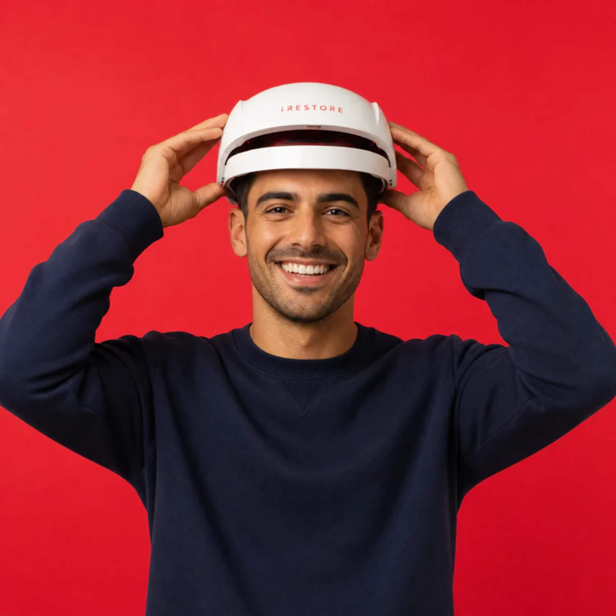 Man putting on iRESTORE Essential laser hair growth cap in navy sweater