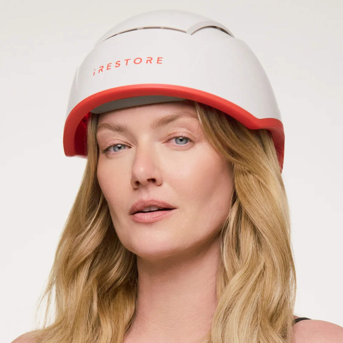 Woman wearing the iRESTORE Professional Hair Growth System on a light background