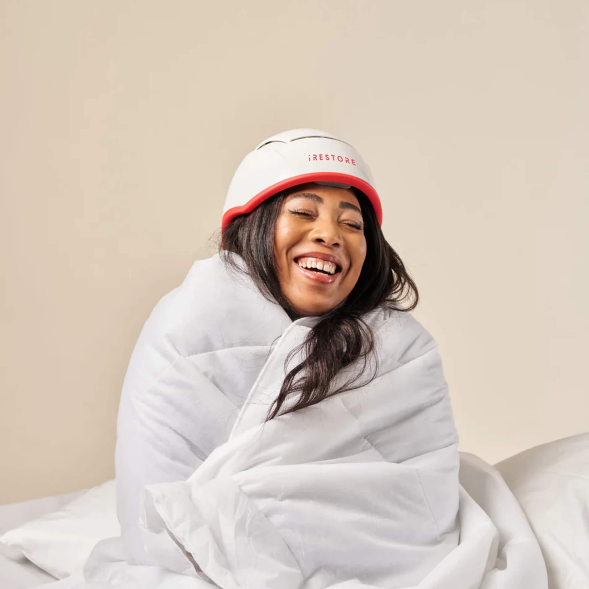 Woman relaxing in a blanket while wearing the iRESTORE Professional laser hair growth cap