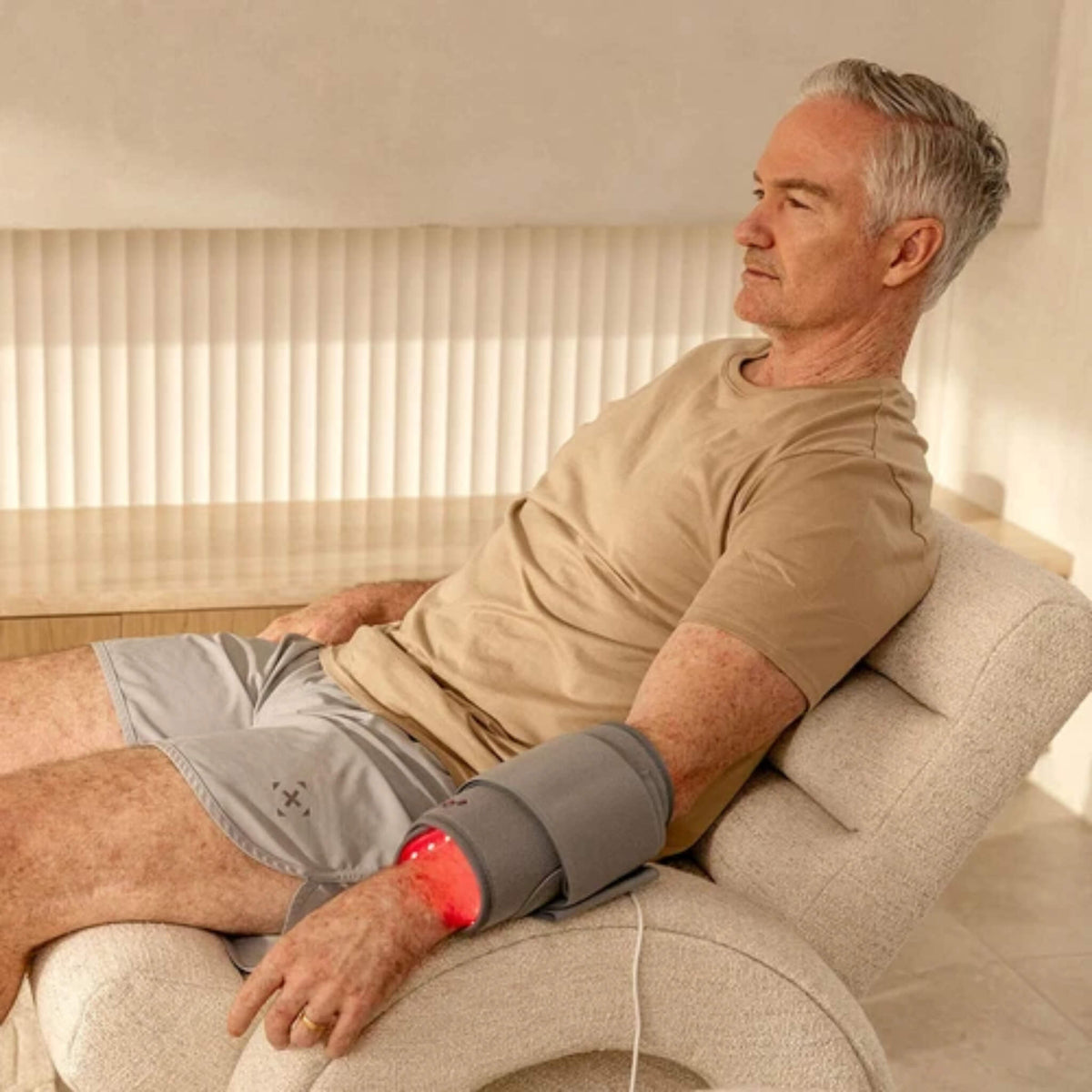 Man relaxing in a chair with the NovaaLab Novaa Light Pad strapped around his forearm