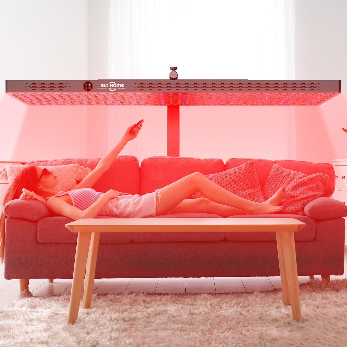 Woman lying on a couch at home under the RLT Home Total Spectrum ELITE Red Light Therapy Device set horizontal