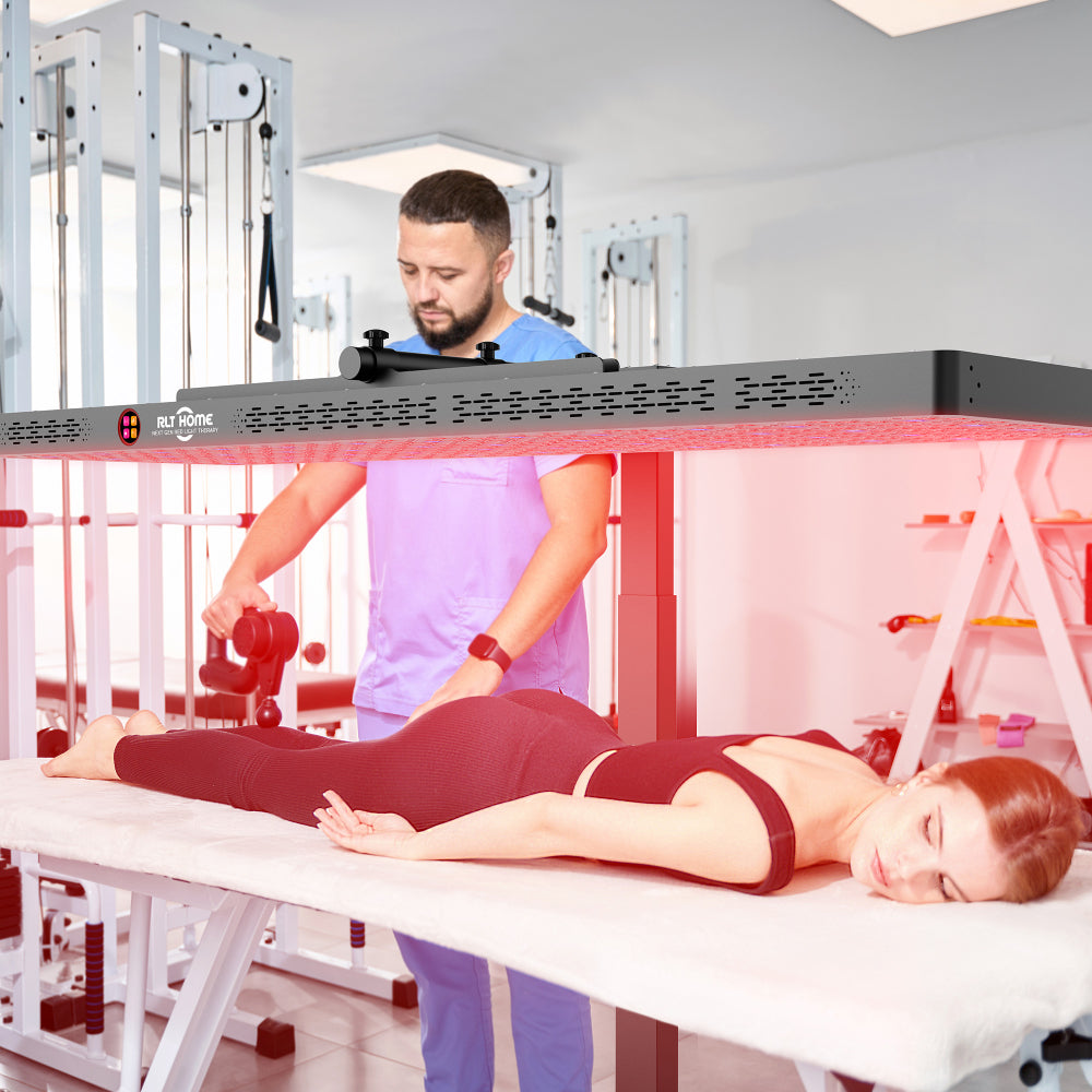Man standing beside a woman lying on a treatment table under the RLT Home Total Spectrum ELITE Red Light Therapy Device