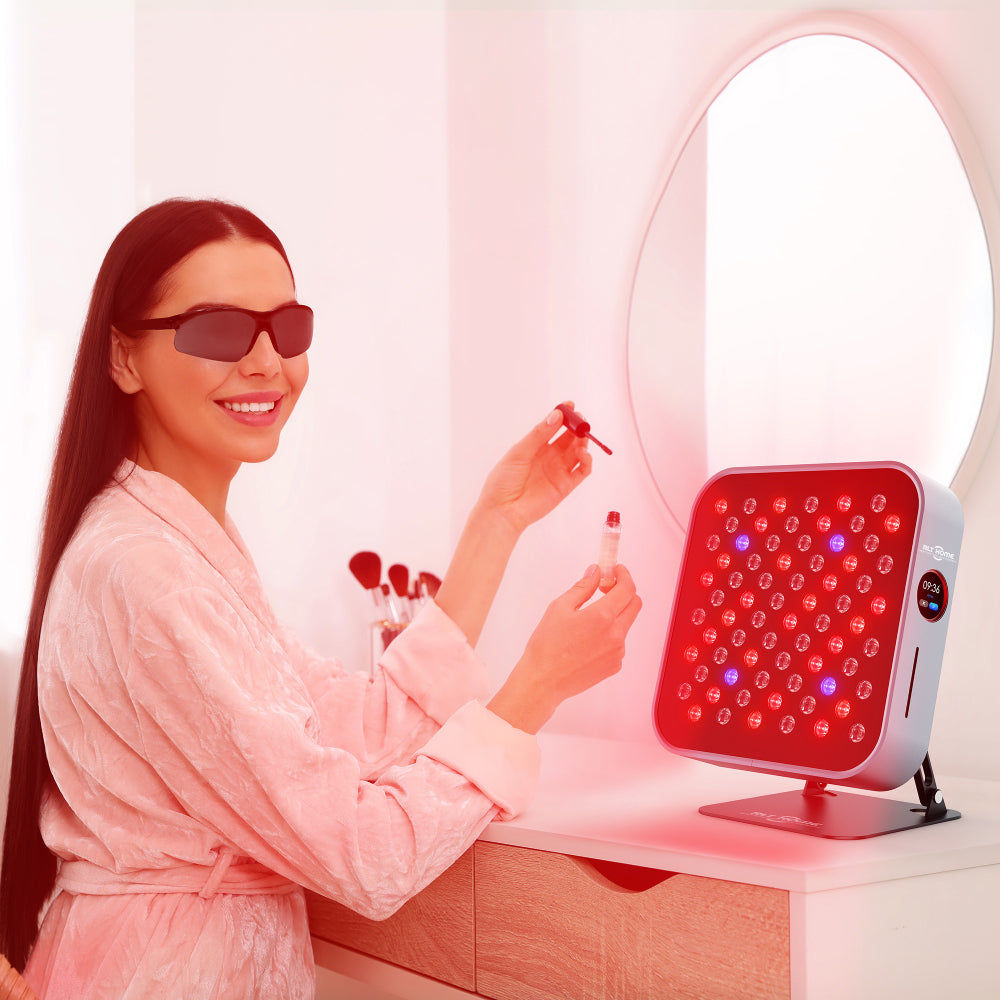 Woman wearing eye protection at a desk facing the RLT Home Total Spectrum MINI Red Light Therapy Device